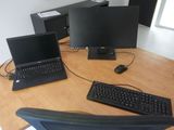 trois ordinateurs portables et un clavier posés sur un bureau en bois