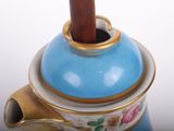 a blue and gold teapot with a wooden stick sticking out of it