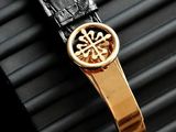 an image of a gold watch with a black leather strap