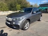 La BMW X5 est garée sur un parking près d'un immeuble.
