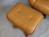 a brown leather chair and ottoman on a white surface