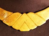 a gold necklace with a bird shaped design on it