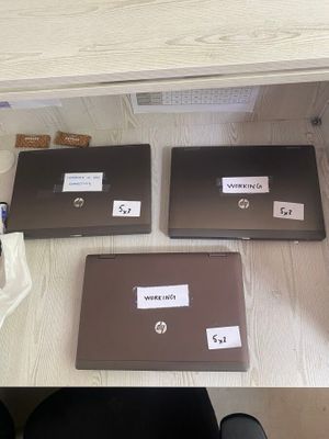 trois ordinateurs portables posés sur un bureau, sur lesquels sont apposées des étiquettes