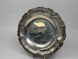 un plat ancien en argent orné d'un oiseau, posé sur un socle
