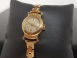 an image of a gold wrist watch on a black cushion