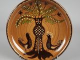 une assiette marron décorée d'oiseaux et d'un arbre