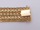 a close up of a gold bracelet with a clasp on a white surface