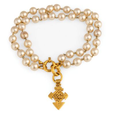 un bracelet en perles et en or orné d'une breloque en forme de croix