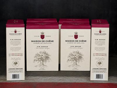 trois cartons de vin posés sur une étagère devant un mur noir