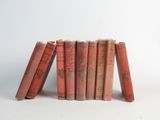 several old books stacked on top of each other on a white surface
