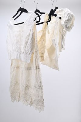 three white dresses hanging on a clothes rack against a white wall