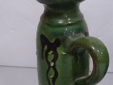 a green vase with a horse on it sitting on a table