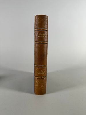 un vieux livre posé sur une table à côté d'une tasse
