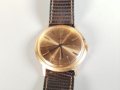 une montre en or avec un bracelet marron sur un fond blanc