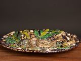 a decorative plate with a lizard on it sitting on a table