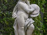a statue of a child holding a bowl in a garden