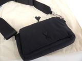 a black purse with a black strap on a bed