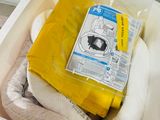 a white container with a yellow bag of diapers inside of it