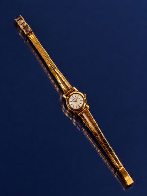 a gold watch on a blue surface