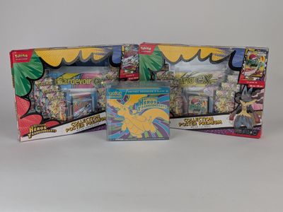trois cartes à collectionner Pokémon différentes dans une boîte posée sur une surface blanche