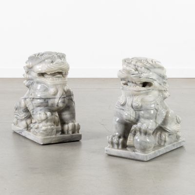pair of white marble foo foo foo statues sitting on top of a gray floor