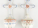 two spoons with a cross on them hanging on a wall