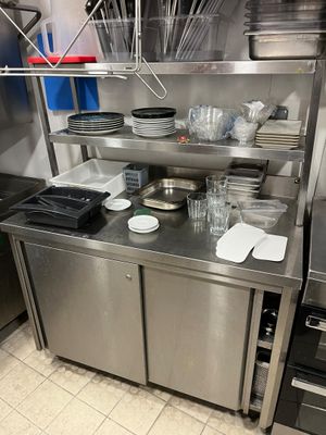 une cuisine en inox avec de nombreux plats et ustensiles posés sur le plan de travail
