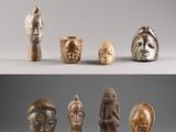Plusieurs types de masques africains sont exposés sur un fond gris.