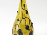 un vase jaune orné de feuilles noires