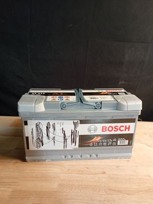 two bosch batteries on a wooden table with a black background