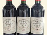 trois bouteilles de vin rouge sont alignées sur une surface blanche