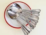 a red and white plate with silver spoons on it