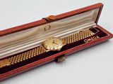 a gold watch in a red box on a white surface