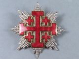 a close up of a red and gold cross brooch on a table