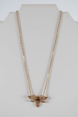 un collier en or avec un pendentif en forme d'abeille autour du cou d'un mannequin