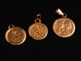 trois pendentifs en forme de pièces d'or sur fond noir, avec un fond noir