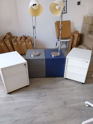 une pièce avec un bureau, une chaise, une lampe et quelques cartons