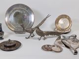 a silver plate with a bird on it next to other silver objects