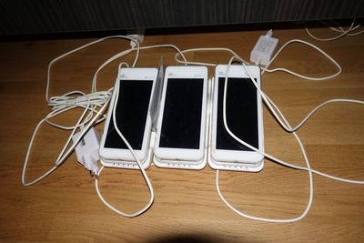 three white cell phones sitting next to each other on a wooden table