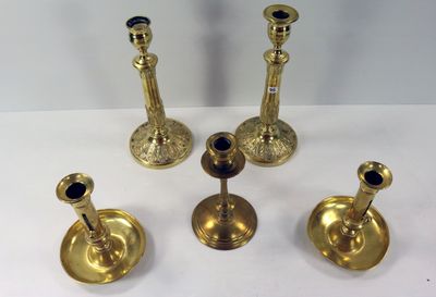 trois bougeoirs en or et un porte-bougie posés sur une surface blanche