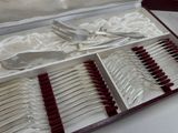 silverware in a case with red handles and spoons on a table
