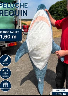 a man holding a large stuffed shark in front of a truck
