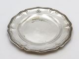 an antique silver plate on a white surface with a silver rim