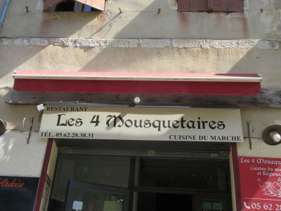 une enseigne indiquant « Les 4 mousquetaires » sur la façade d'un immeuble