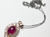 une chaîne en argent avec un pendentif orné d'une pierre rouge, posée sur un fond blanc