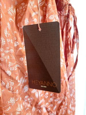 une robe orange avec une étiquette noire qui pend sur le côté