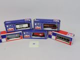 quatre boîtes contenant des trains miniatures, posées sur une surface blanche