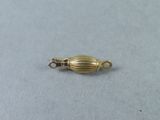 a close up of a gold plated bead on a white surface
