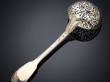 une cuillère en argent dont le manche repose sur une surface noire