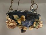 a hanging planter with flowers and leaves on it